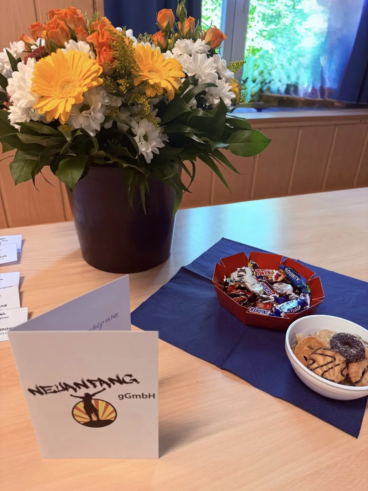 erfolgreiche-abschluesse-2 Ein Blumenstrauß mit bunten Blumen und eine Schale mit Süßigkeiten auf einem Tisch.